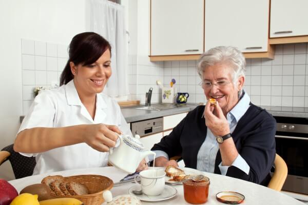 Elderly lady and caregiver enjoying breakfast together.